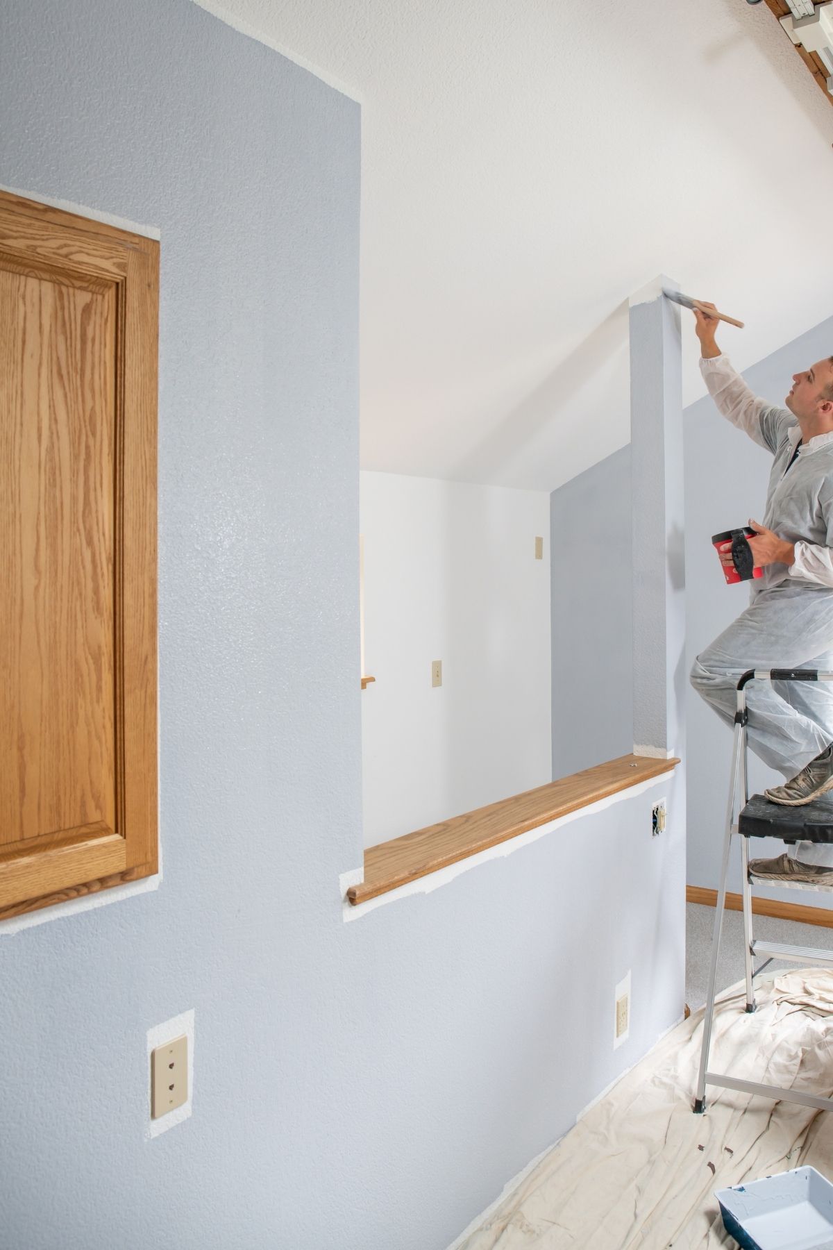 Peintre professionnel utilisant un rouleau pour peindre un mur intérieur à Sainte-Julie
